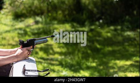 Gas aus der Mündung einer BB-Luftpistole. Die Kugel ist vor der Waffe zu sehen. Stockfoto