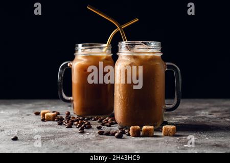 Mason Gläser mit leckerem Eiskaffee mit Milch, Bohnen und Zuckerwürfeln auf dem Tisch Stockfoto