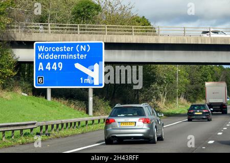 Worcester, England - 2021. Oktober: Auto, das an einem Straßenschild auf der Autobahn M5 vorbeifährt und die Fahrer über eine Kreuzung nach Kidderminster und Worcester informiert. Stockfoto