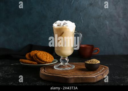 Glastasse aus vereister Hojicha Latte und Pulver auf schwarzem Hintergrund Stockfoto