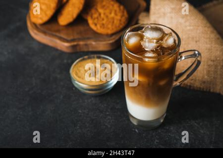 Glastasse aus vereister Hojicha Latte auf schwarzem Hintergrund Stockfoto