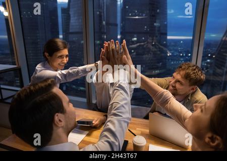 Glückliche junge Mitarbeiter mit gemischter Rasse feiern gemeinsamen Erfolg. Stockfoto
