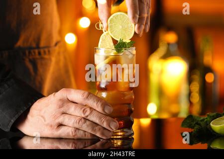 Der Barkeeper drückt Limette in einem Glas leckeren Cuba Libre-Cocktail auf den Tisch in der Bar Stockfoto