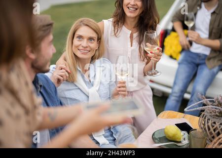 Freunde trinken Wein bei Picknick in der Nähe von Weinbergen Stockfoto