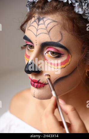 Junge Frau bereitet sich auf die Feierlichkeiten zum mexikanischen Tag der Toten vor (El Dia de Muertos) Stockfoto