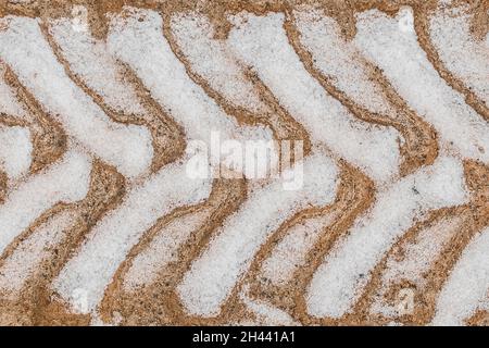 Spuren und Muster von den Reifen der Räder des industriellen Transports auf dem Boden im Winter Hintergrund. Stockfoto