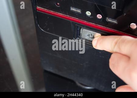 Man drückt mit dem Finger auf einen Ausschalter eines Heimcomputers. Stockfoto