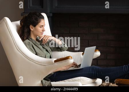 Frau sitzt im Sessel Kauf auf Internet Laptop verwenden Stockfoto