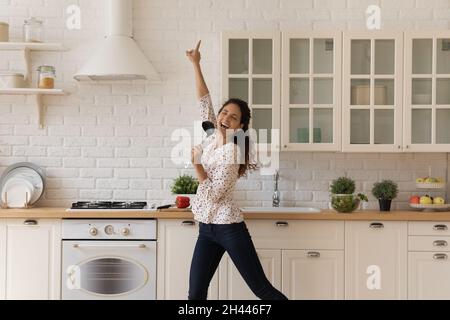 Frau abgelenkt vom Kochen, hält Schöpfkelle singen Tanz in der Küche Stockfoto