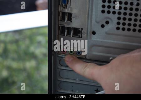 Zeigen Sie mit dem Finger auf die hinteren Anschlüsse eines Heimcomputers. Stockfoto