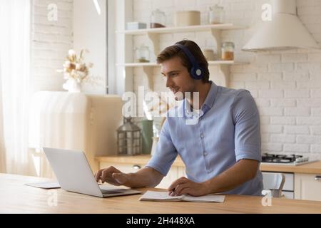 Mann benutzen Laptop, der Informationen im Copybook e-Learning zu Hause notiert Stockfoto