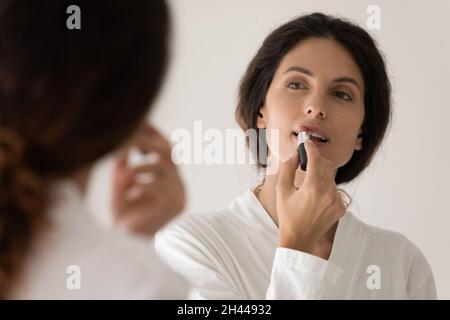 Frau im Bademantel, die Lippenstift auf die Lippen auflegt Stockfoto