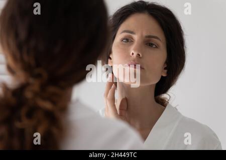 30s Frau sieht in Spiegel berühren Gesicht fühlt sich aufgeregt Stockfoto