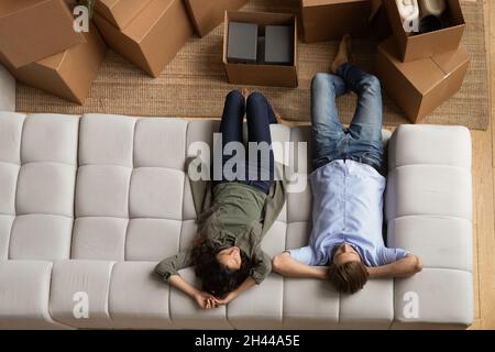 Oben sehen Paar auf dem Sofa liegend, das sich am Umzugstag ausruhte Stockfoto