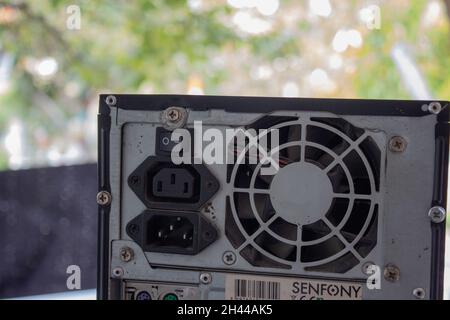 Drücken Sie den ein-/Ausschalter am Netzteil eines Computers mit einem Finger, während Sie einen gelben Schraubendreher halten. Stockfoto