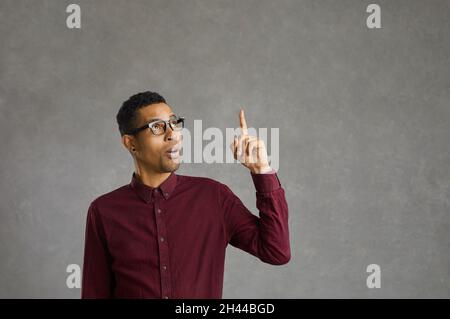 Junger hispanischer Mann, der eine Brille auf einem isolierten schwarzen Hintergrund trägt und eine Handbewegung macht Stockfoto