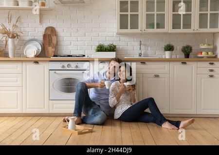 Paar entspannen auf dem Boden in der Küche hält Tassen trinken Tee Stockfoto