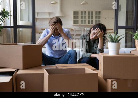 Erschöpfte Paare sitzen am Umzugstag in der Nähe von Kartons Stockfoto