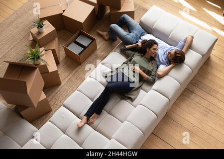 Ein Paar mit Blick von oben, das sich auf dem Sofa in der Nähe von Kartons entspannen kann Stockfoto