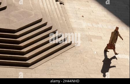 Belgrad, Serbien - 25. Oktober 2020: Ein kahlköpfiger Mann in Anzug und Mantel mit Aktentasche, der alleine die riesige öffentliche Treppe hinuntergeht, mit Blick aus dem hohen Winkel Stockfoto