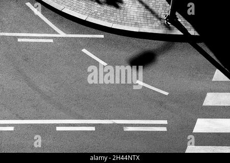 Schatten und Straßenmarkierungen auf der Stadtstraße in schwarz-weiß, von oben Stockfoto