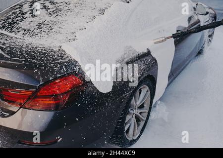 Auto in weißer Seife suds während der professionellen Auto-Reinigung im Freien Stockfoto