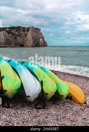 Kajaks in verschiedenen Farben, gestapelt an den Ufern des Atlantiks in Etretat, Normandie Stockfoto