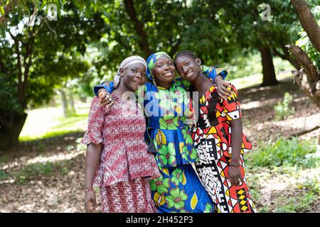 Drei stolze afrikanische Frauen stehen im Grünen und zeigen ihre neuen bunten Kleider Stockfoto