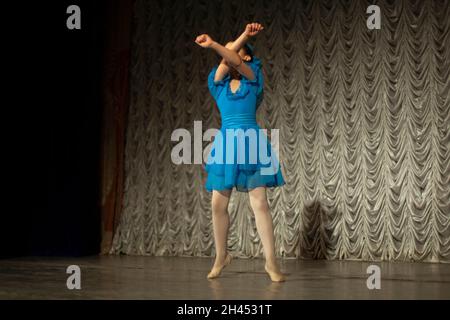 Ein Kind tanzt auf der Bühne. Performance eines Mädchens in einem blauen Kleid. Der Künstler zeigt Rock and Roll. Ein Kind in einer Tanzstunde. Stockfoto