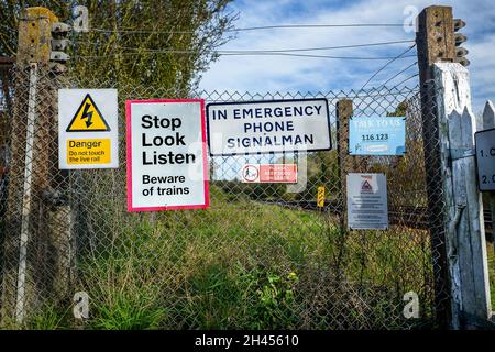 Warnschilder am Zaun am Bahnübergang. Stockfoto