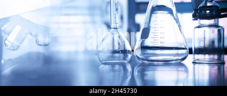 Konische und volumetrische Glaskolben mit Mikroskop und wissenschaftlichen Geräten im Chemielabor lila blauen Banner Hintergrund Stockfoto