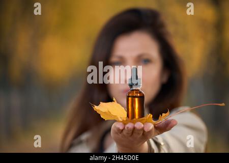 Flasche auf einem Blatt, Handfläche. Eine Frau, die einen Kräuterextrakt für die Immunität hält. Natürliche Resistenz, Konzept. Kräutermedizin. Stockfoto
