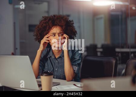 Seriöse hübsche Dame, die viel im Büro arbeitet Stockfoto