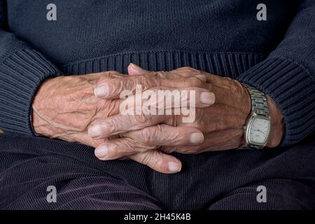 Nahaufnahme der Hände des älteren Mannes, die die Finger kreuzen Stockfoto