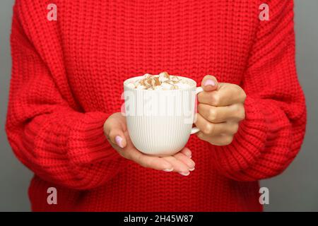 Wintergetränk: becher mit Kakao oder heißer Schokolade mit Marschmalchen in weiblicher Hand, beschnittenes Bild Stockfoto