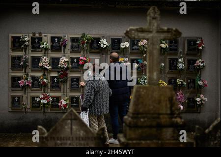 Pamplona, Spanien. Oktober 2021. Zwei Menschen haben vor Kolumbarien auf dem Friedhof von Pamplona gebetet.Anlässlich des Allerheiligen-Tages gehen katholische Familien zum spanischen Berichitos-Friedhof in Pamplona, um Blumen auf die Gräber ihrer verstorbenen Verwandten in Navarra zu legen. Kredit: SOPA Images Limited/Alamy Live Nachrichten Stockfoto