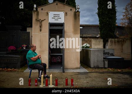 Pamplona, Spanien. Oktober 2021. Ein Mann sieht auf dem Friedhof von Pamplona sitzen und sieht ihn umgeben von Kerzen an.Anlässlich des Allerheiligen-Tages gehen katholische Familien zum spanischen Berichitos-Friedhof in Pamplona, um Blumen auf die Gräber ihrer verstorbenen Verwandten in Navarra zu legen. Kredit: SOPA Images Limited/Alamy Live Nachrichten Stockfoto