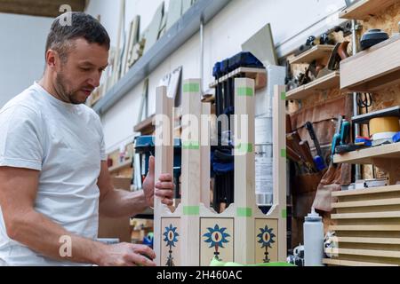 Ein Mann stellt in einer Holzwerkstätte maßgeschneiderte Möbel her, die den Bauprozess zeigen Stockfoto