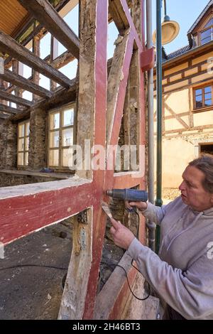 Dernau, Deutschland. Oktober 2021. Der Altbau-Renovierer Linah entfernt mit einem Heißluftgebläse die alte Farbe von den Balken eines Fachwerkhauses, von dem die Flut nur ein Skelett zurückließ. Die tödliche Sturzflut im Ahrtal hat auch Hunderte historischer Fachwerkhäuser beschädigt oder zerstört - Bewohner und Behörden versuchen, so viele wie möglich zu retten. (Zu dpa: Fachwerkhäuser auch von Hochwasser betroffen - viele zu retten). Quelle: Thomas Frey/dpa/Alamy Live News Stockfoto