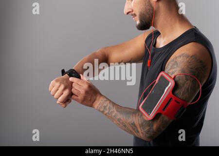 Fit muskulösen Mann Check Fitness-Trekker auf Smartwatch nach dem Joggen am Morgen Stockfoto