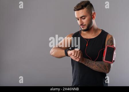 Porträt eines Sportlers, der nach dem Training im Fitnessstudio die Herzfrequenz auf dem Fitness-Trekker überprüft Stockfoto