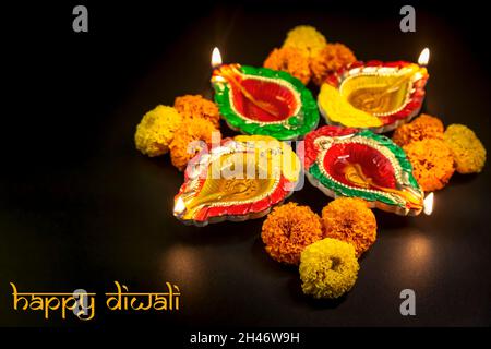 Diwali traditionelle Diya-Lampen aus Lehm, verziert mit Ringelblumen auf dunklem Hintergrund Stockfoto