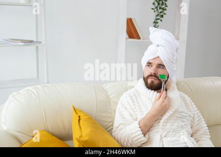 Bärtiger Mann mit Gesichtsmassage-Werkzeug. Männliches Hautpflege- und Spa-Konzept. Stockfoto