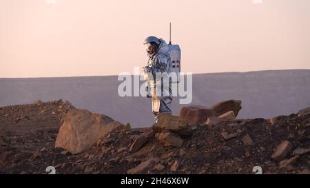 Ein analoger Astronaut, gekleidet in einen speziellen Raumanzügen, umläuft einen Rover auf dem Gelände der Mars-ähnlichen Forschungseinrichtung, die für die AMADEE-20-Mars-Simulation am Ramon-Krater in der Negev-Wüste in Israel gebaut wurde. Sechs Analogastronauten aus Israel, Portugal, Spanien, Deutschland, den Niederlanden und Österreich haben eine dreiwöchige Isolation innerhalb der Forschungseinrichtung abgeschlossen und konnten ihren Lebensraum nur in Raumanzügen verlassen. Das Team führte eine Reihe von wissenschaftlichen und technologischen Experimenten durch, in der Hoffnung, die Grundlagen für zukünftige bemannte Missionen zum Mars zu schaffen. Stockfoto