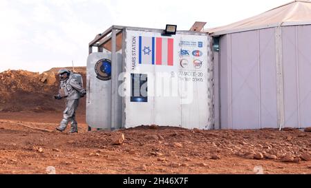 Ein analoger Astronaut, gekleidet in einen speziellen Raumanzügen, macht einen Spaziergang um die Mars-ähnliche Forschungseinrichtung, die für die AMADEE-20-Mars-Simulation am Ramon Crater am 31. Oktober 2021 in der Negev-Wüste in Israel gebaut wurde. Sechs Analogastronauten aus Israel, Portugal, Spanien, Deutschland, den Niederlanden und Österreich haben eine dreiwöchige Isolationszeit innerhalb der Forschungseinrichtung abgeschlossen und konnten ihren Lebensraum nur in Raumanzügen verlassen. Das Team führte eine Reihe von wissenschaftlichen und technologischen Experimenten durch, in der Hoffnung, die Grundlagen für zukünftige bemannte Missionen zum Mars zu schaffen. Stockfoto