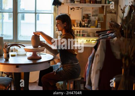 Die Töpferin Frau sitzt in einer Vase mit Bildhauerei im Studio. Geschäftsfrau entspannen nach der Arbeit in der Werkstatt Stockfoto