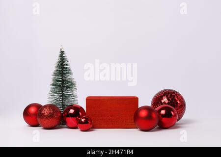 Abstrakt minimalistischer weihnachtshintergrund, rotes Holzpodium, Kugeln und weihnachtsbaum. Winterbühne für Ihre Produkte Stockfoto