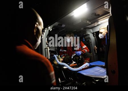 PRODUKTION - 11. Oktober 2021, Baden-Württemberg, Neuhausen auf den Fildern: Notarzt Dr. Christoph Herzog (m) bereitet den Patienten im Rettungshubschrauber auf den Transport in ein Krankenhaus vor, während ihm die beiden Piloten Matthias Fleisch (l) und Roy Fleischer (r) zur Seite stehen. Der Rettungshubschrauber Christoph 54 ist der einzige in Baden-Württemberg, der auch Nachtflugkapazitäten hat. Die Nachtcrew mit den beiden Piloten übernimmt die fliegende Intensivstation von 6.30 Uhr abends bis 7 Uhr am nächsten Morgen. Er ist auf dem Bahnhof Villingen-Schwenningen der Deutschen Luftwaffe stationiert Stockfoto