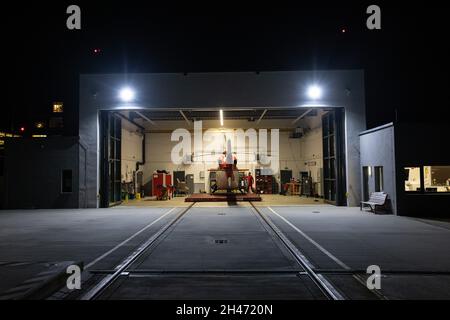 PRODUKTION - 11. Oktober 2021, Baden-Württemberg, Villingen-Schwenningen: Pilot Roy Fleischer steht neben dem Rettungshubschrauber im hell erleuchteten Hangar. Der Rettungshubschrauber Christoph 54 ist der einzige in Baden-Württemberg, der auch Nachtflugkapazitäten hat. Die Nachtcrew mit den beiden Piloten übernimmt die fliegende Intensivstation von 6.30 Uhr abends bis 7 Uhr am nächsten Morgen. Sie ist auf der Station Villingen-Schwenningen des Deutschen Luftrettungsdienstes (DRF) stationiert und fliegt von dort aus Einsätze im ganzen Land, obwohl es sicherlich Flüge außerhalb gibt Stockfoto