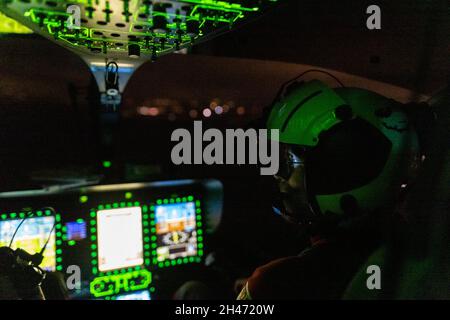 PRODUKTION - 11. Oktober 2021, Baden-Württemberg, Stuttgart: Ein Nachtsichtgerät beleuchtet die Augen und die Brille des Piloten Roy Fleischer, während die Fluginstrumente des Rettungshubschraubers um ihn herum leuchten. Der Rettungshubschrauber Christoph 54 ist der einzige in Baden-Württemberg, der auch Nachtflugkapazitäten hat. Die Nachtcrew mit den beiden Piloten übernimmt die fliegende Intensivstation von 6.30 Uhr abends bis 7 Uhr am nächsten Morgen. Sie ist auf der Station Villingen-Schwenningen des Deutschen Luftrettungsdienstes (DRF) stationiert und fliegt von dort aus Einsätze durch die gesamte Stockfoto